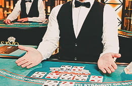 Image of a live casino poker dealer's hands, atop a poker table
