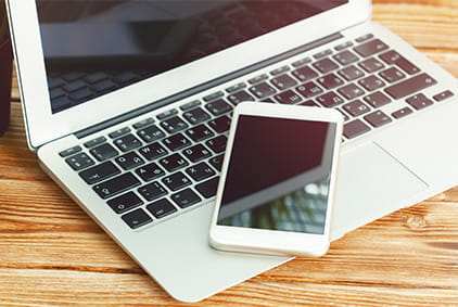 Man Holding Smartphone in Front of Laptop