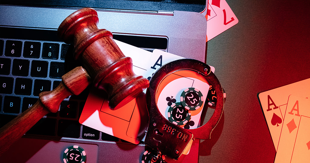 A gavel sat against a laptop keyboard and playing cards