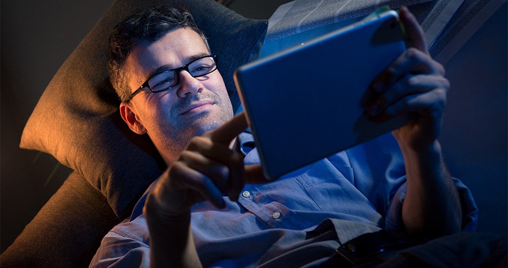 Man gambling on tablet at night