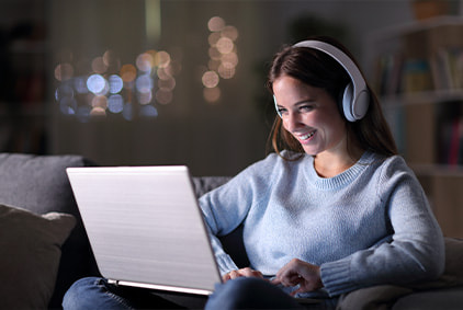 Woman with headphones sitting with a laptop