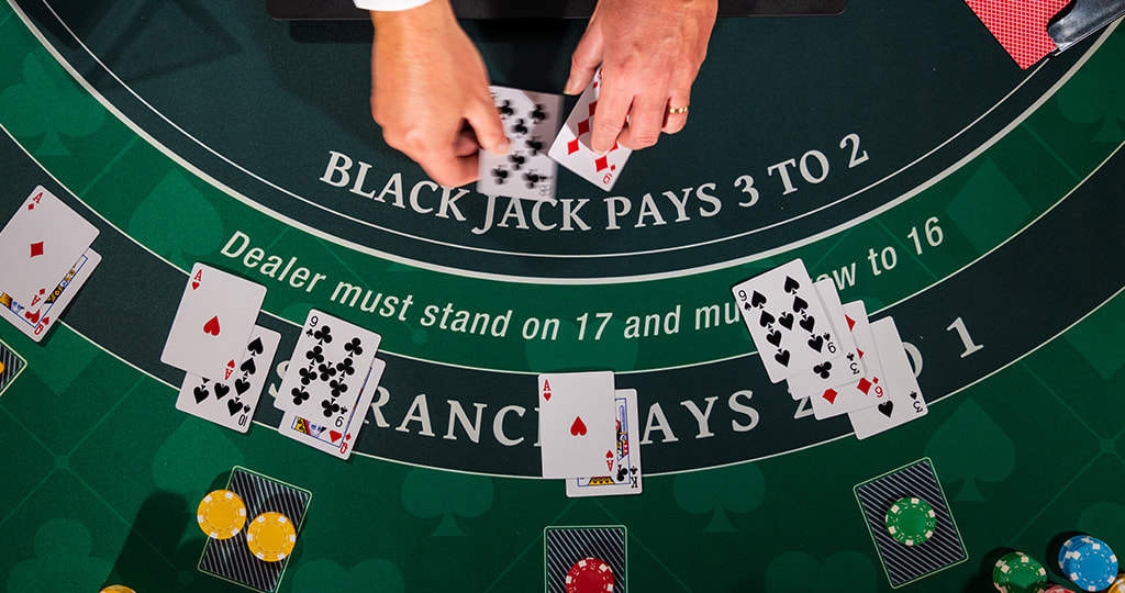 Hands and chips perched on a blackjack table