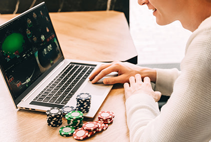 Man playing on a laptop with gambling chips