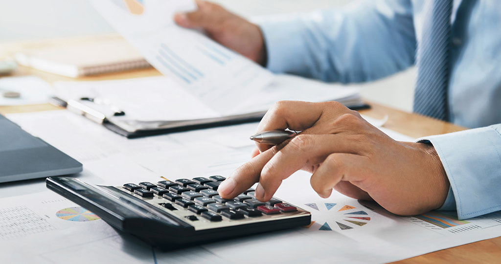 An individual using a calculator and handling paperwork