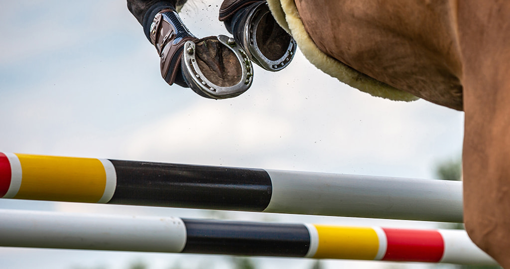 A blurred image of horses jumping a fence