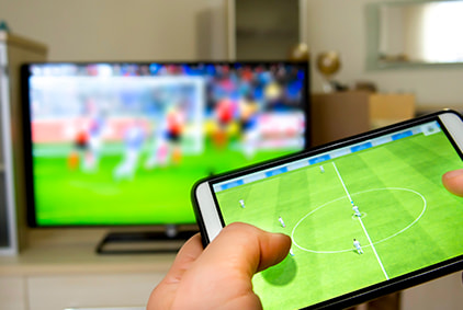 A football match being streamed on a TV and smartphone