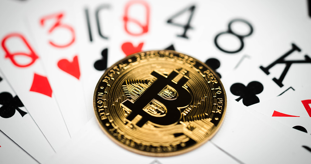 A hand holding playing cards by the BTC symbol