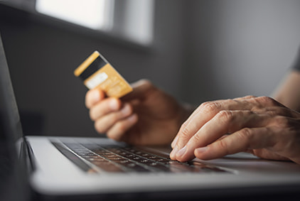 Man holding a credit card at a computer screen