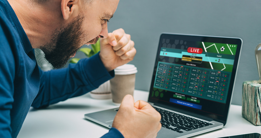 A man placing bets in front of a laptop screen