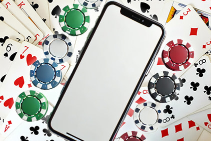 A smartphone being held by chips and playing cards