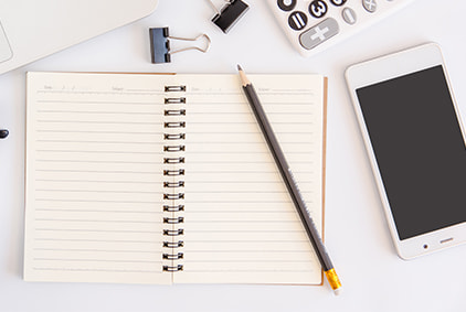 An image of a smartphone, notepad and pen