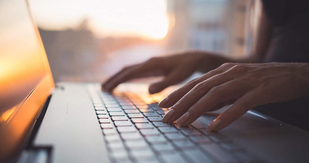 A hand holding an empty wallet by a laptop keyboard